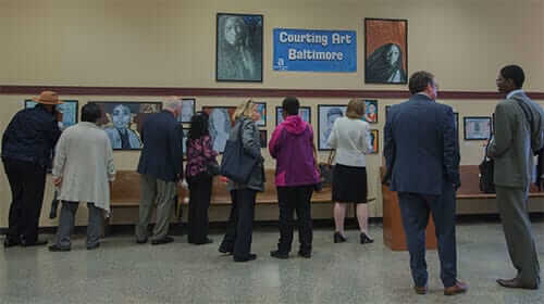 Attendees looking at paintings at a Courting Art Baltimore event